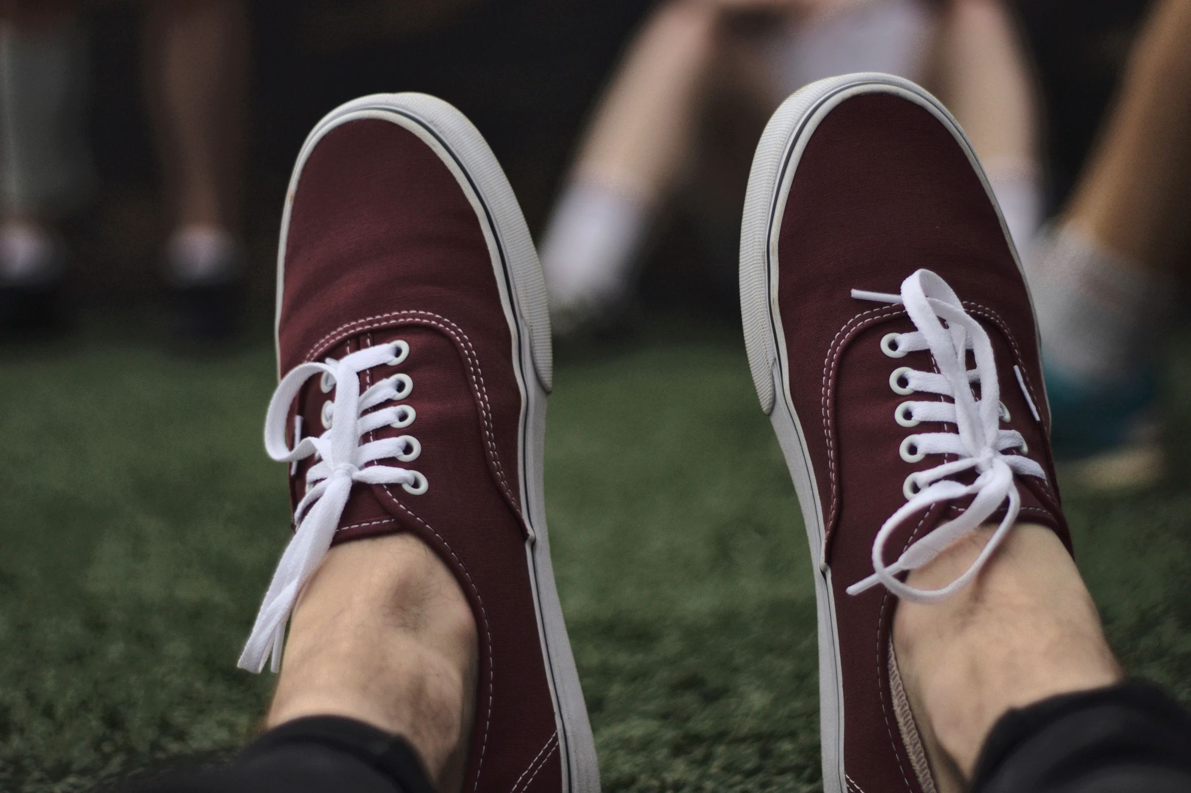 a person's feet standing in grass with other people wearing red and white shoes