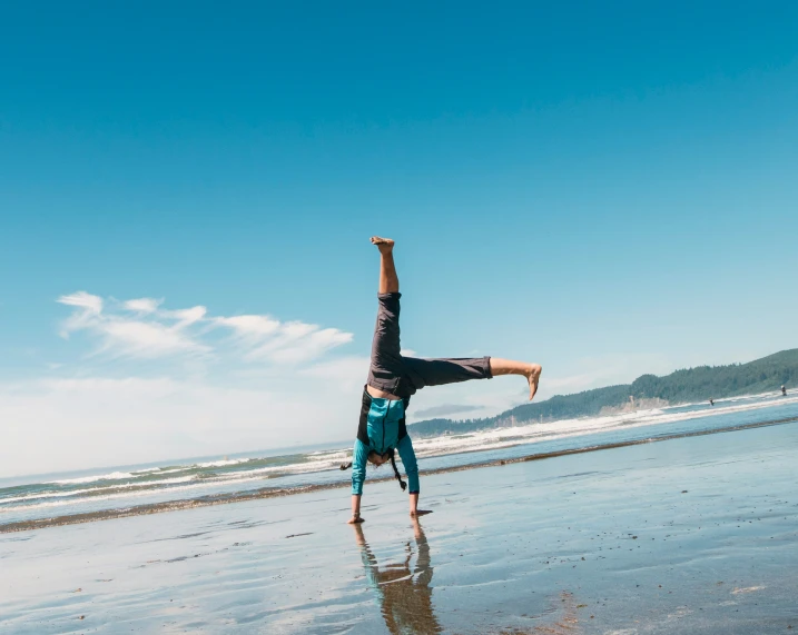 a person doing a handstand on the beach