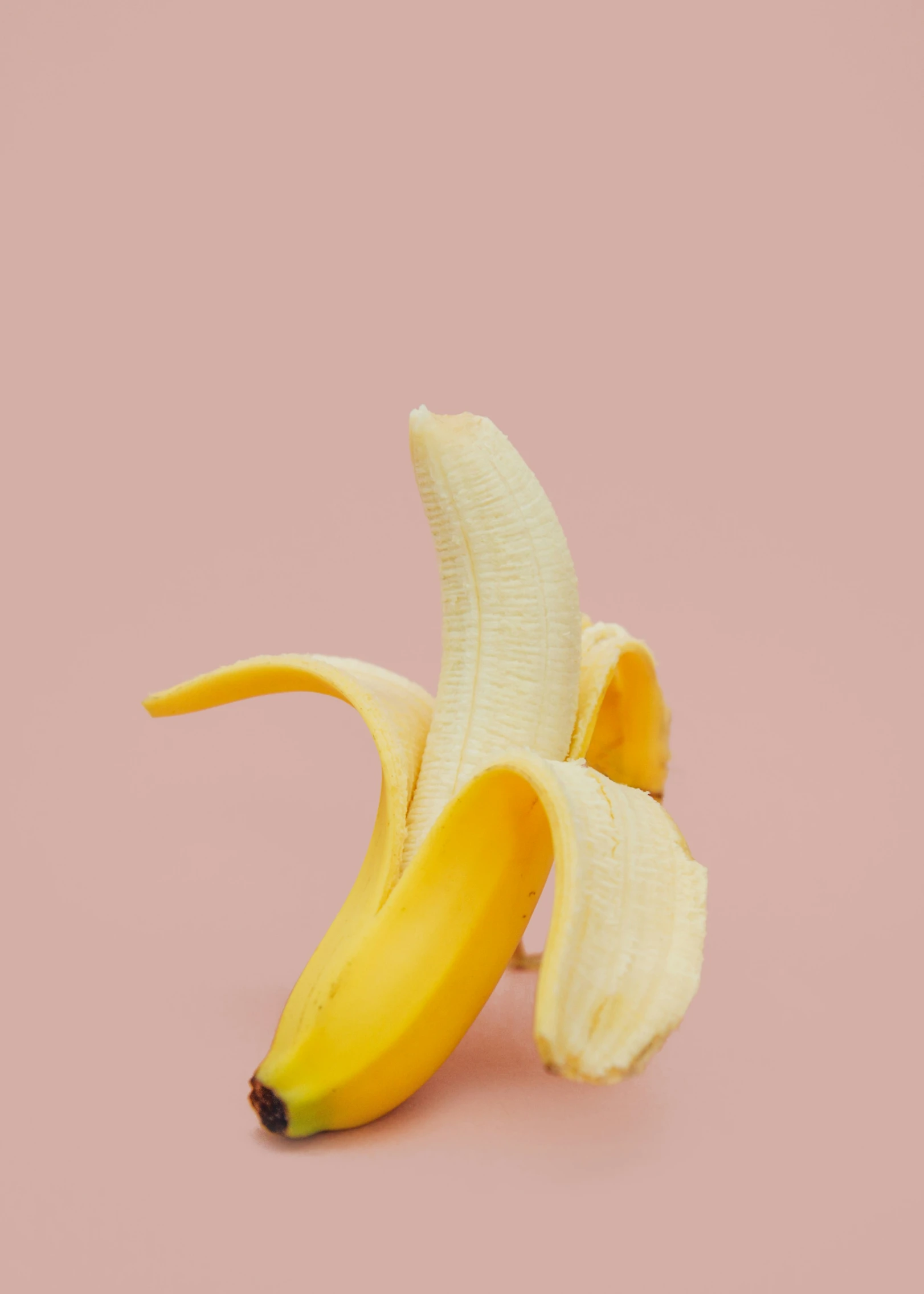 the banana is half peeled but still attached