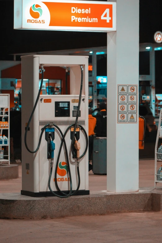 the gas station has two large pumps and people in cars