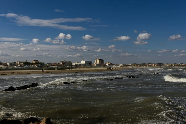 a beach with buildings and crashing waves