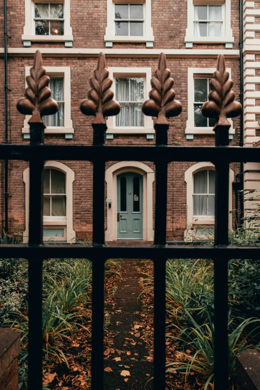 a po taken through a fence of an empty area with a house in the background