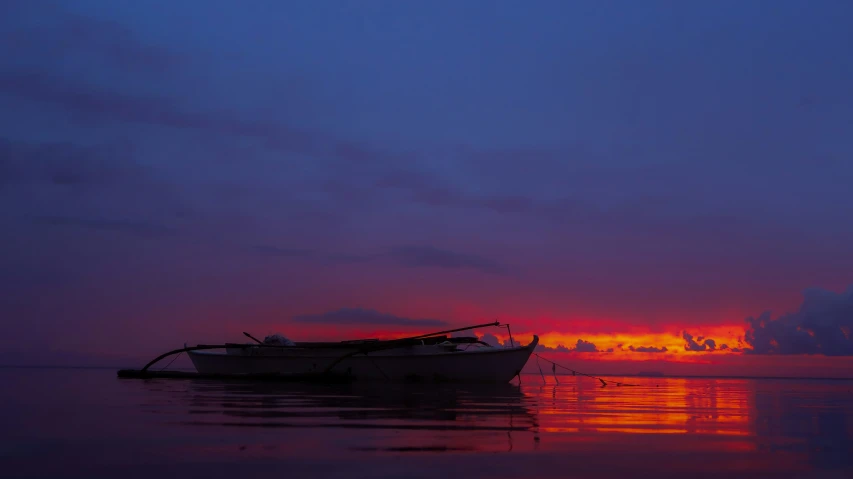 a boat floating on top of a lake at dusk