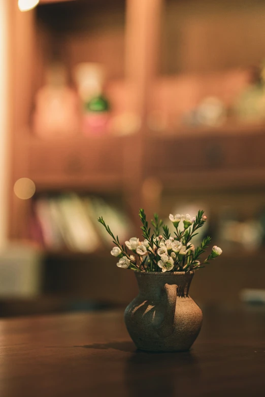 vase with flowers and green stems on a wooden table