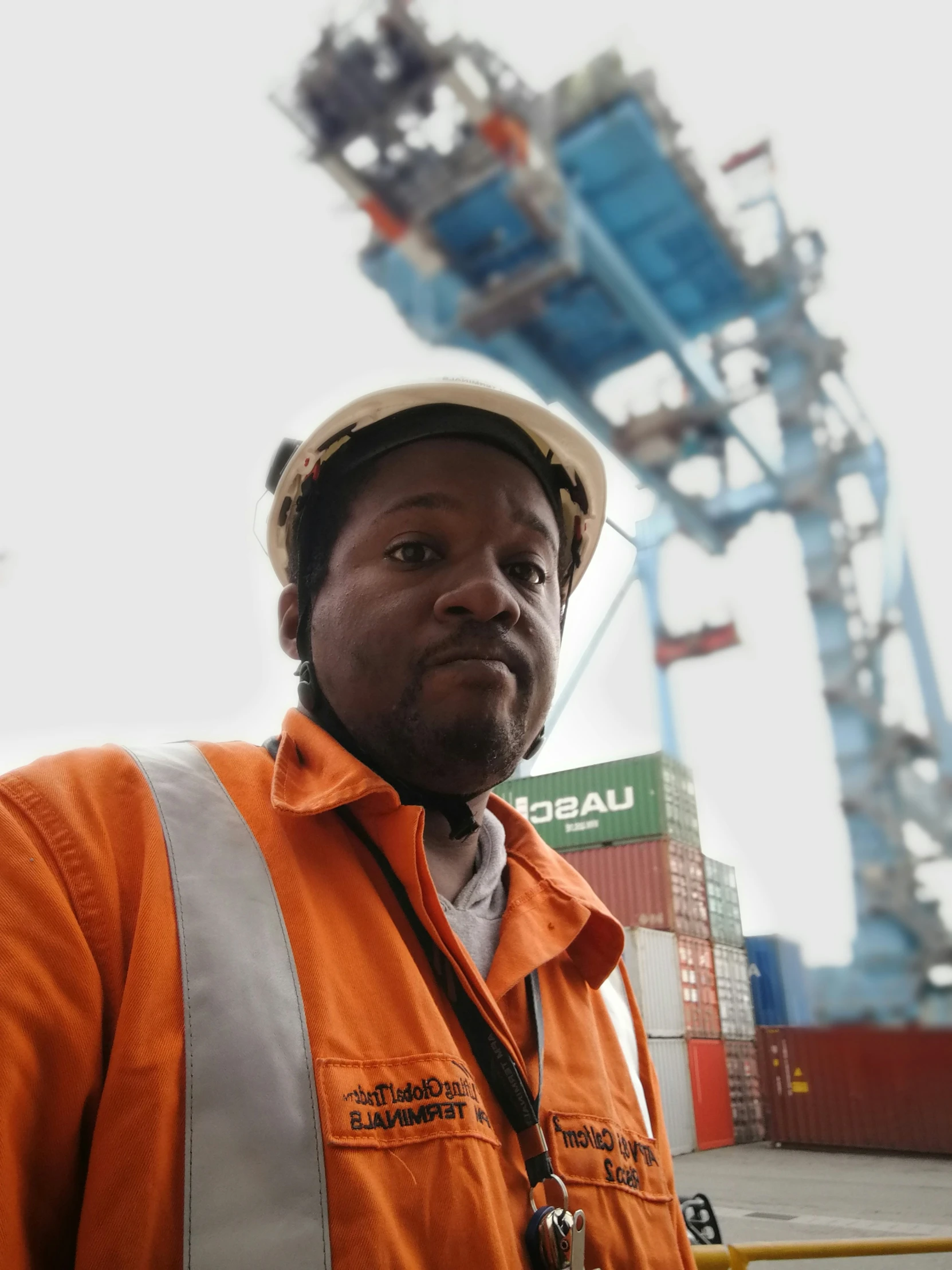 a man wearing a hard hat standing in front of a crane