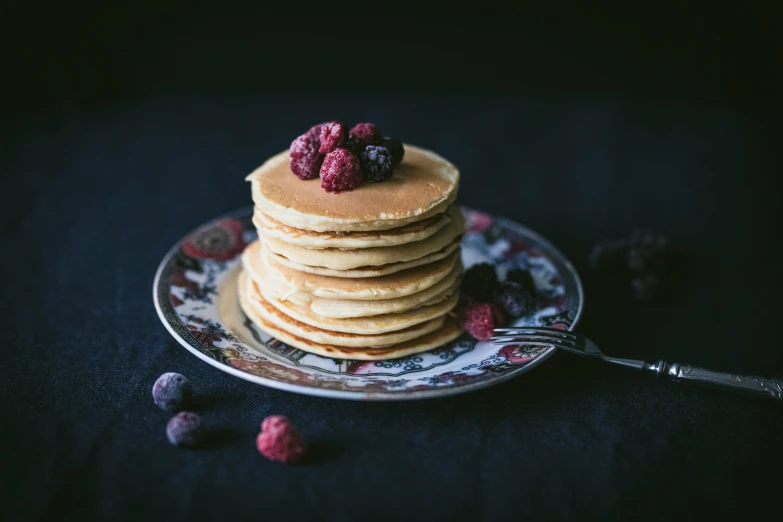 the stack of pancakes has raspberries on top