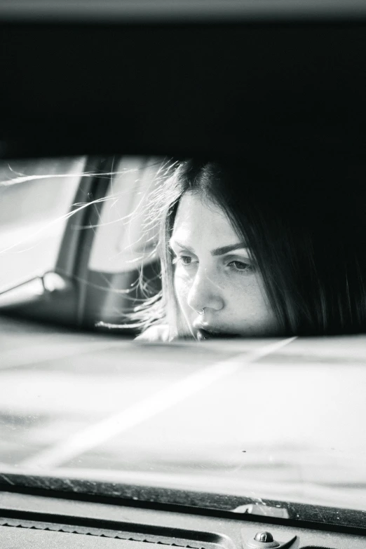 a woman looks in a car mirror that reflects the image of herself