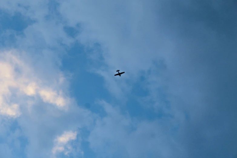 an airplane flies through the clouds in a blue sky