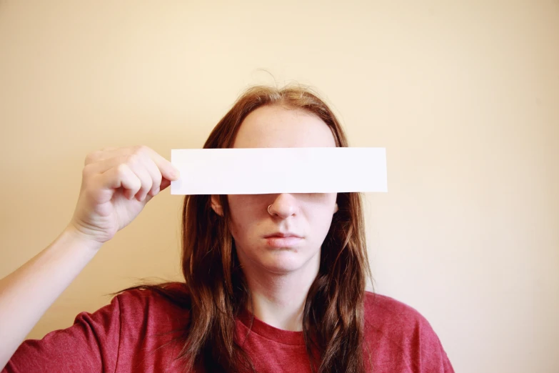 a woman in a red shirt has a piece of paper over her eye