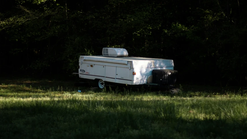 a recreational truck in the shade in a field