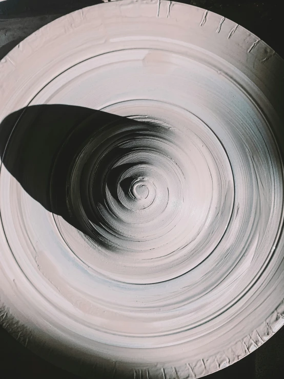 white bowl sitting in middle of large circular pottery vessel