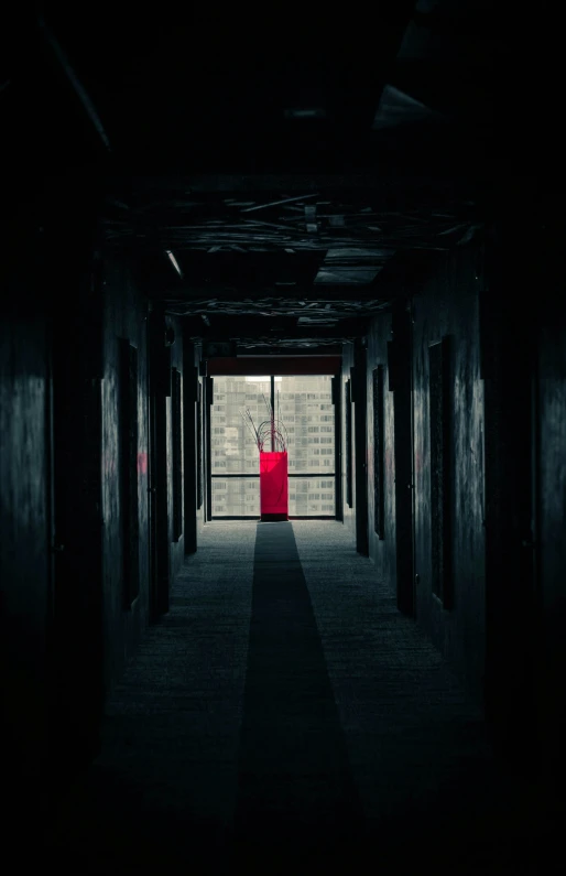 a dark hallway with a bright red chair and vase on the door
