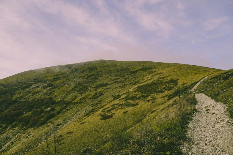 a narrow path winds through green rolling hills