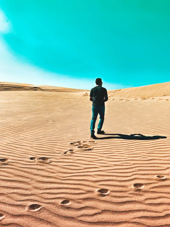 a person standing on sand dunes with footprints