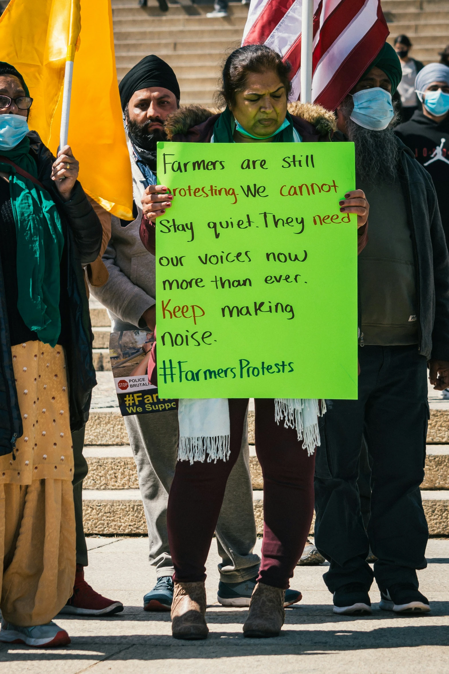 four people outside wearing masks holding protest signs