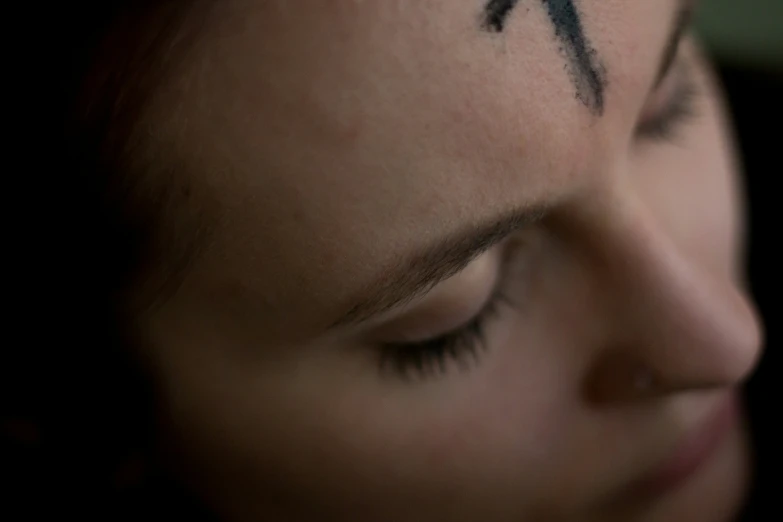 a woman is showing her cross tattoo on her cheek