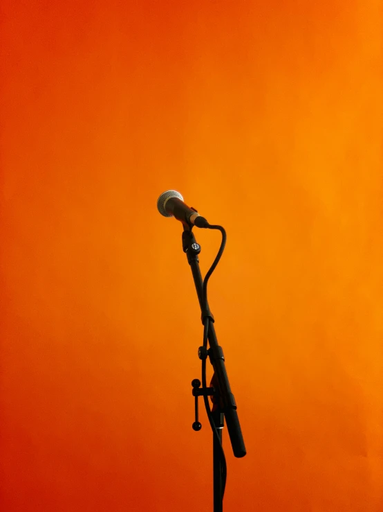 a microphone sits against an orange backdrop