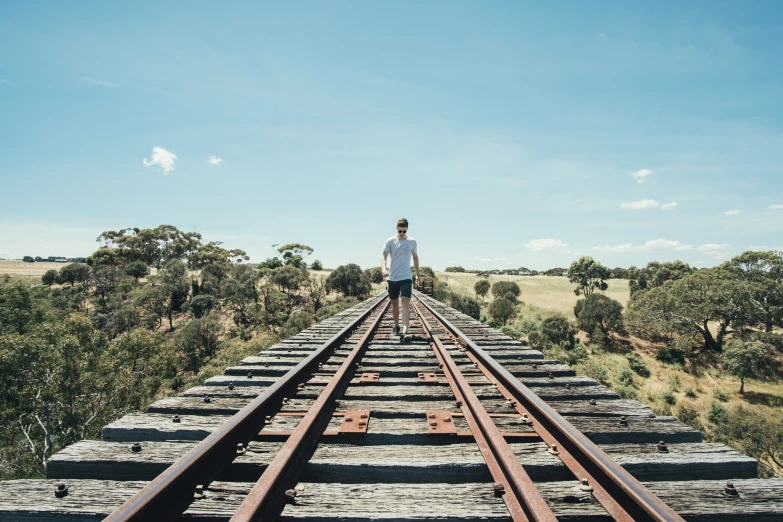 a man standing on the train tracks above the trees