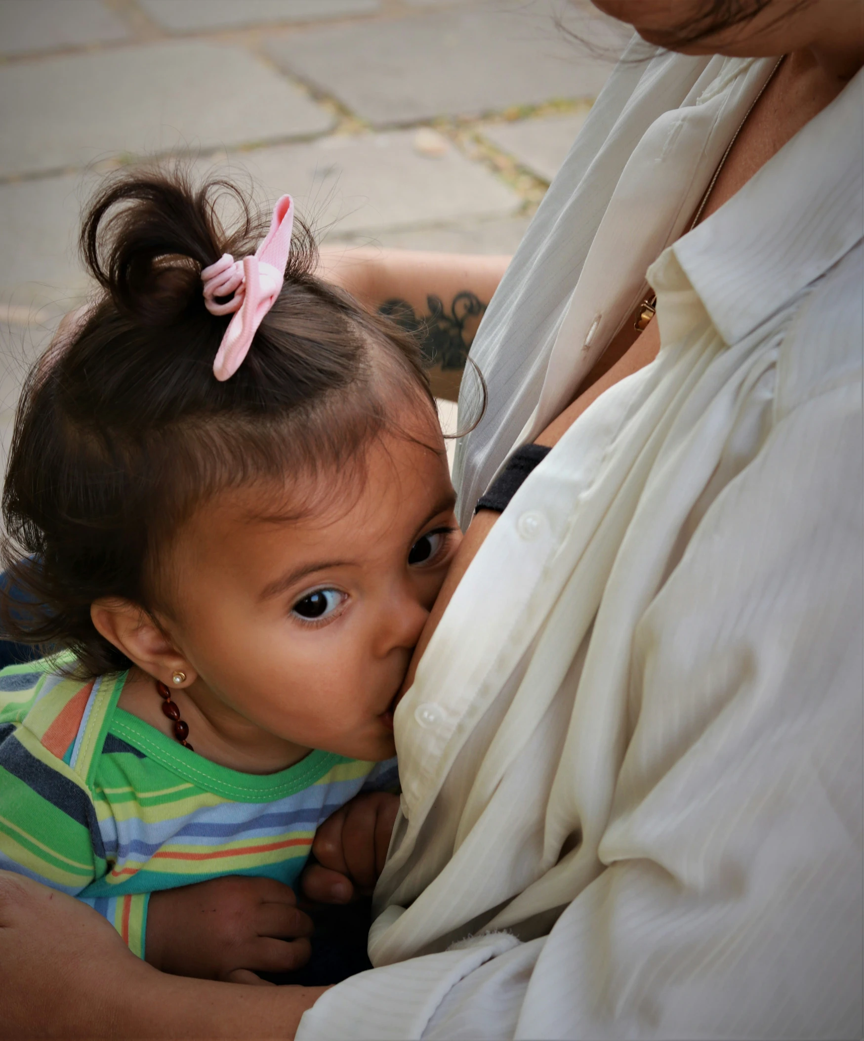 a baby is biting the side of a woman's shirt