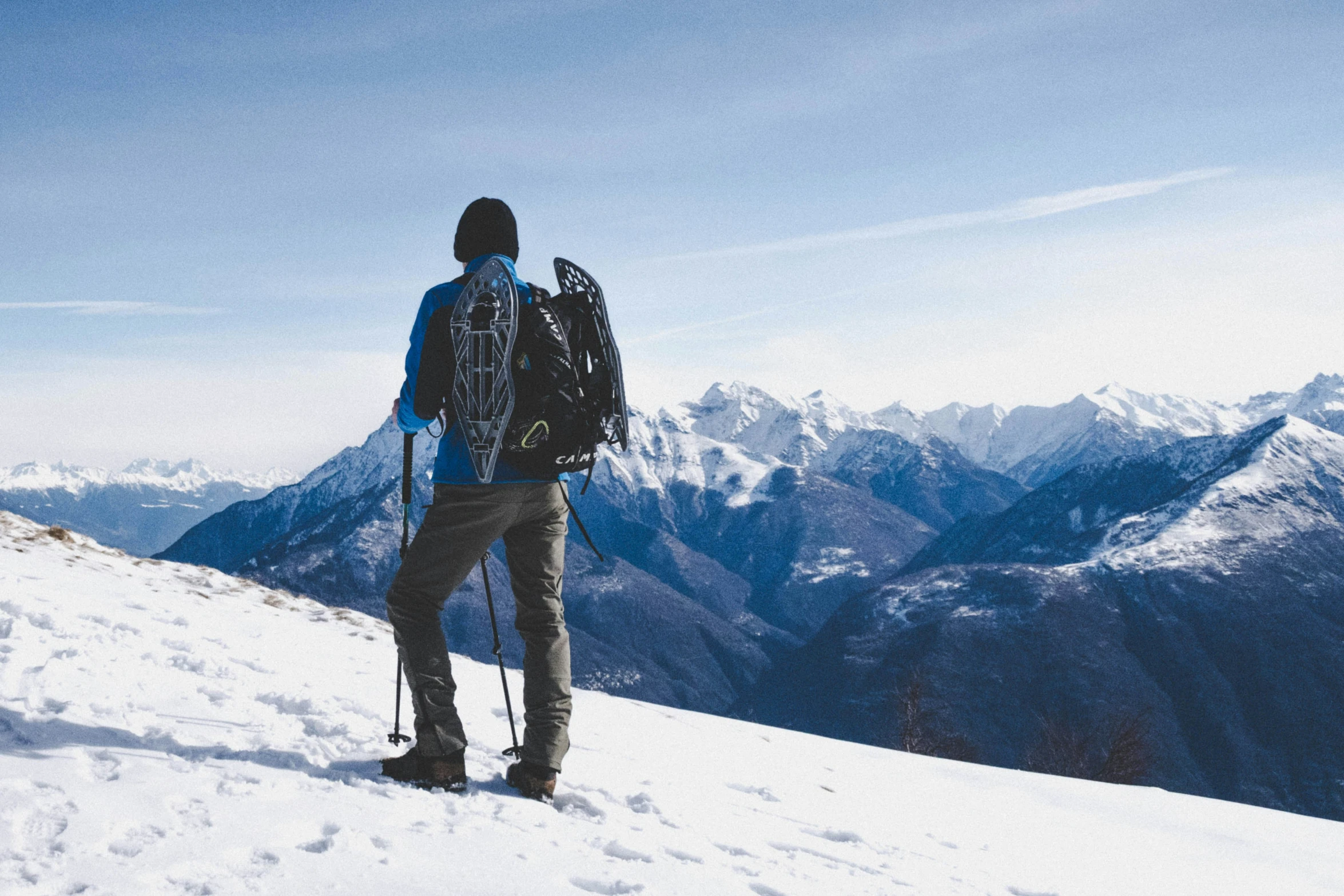 person on skis standing on snowy hill with mountain ranges in the distance