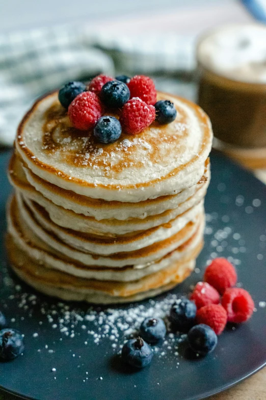 stack of pancakes with berries and powdered sugar on plate