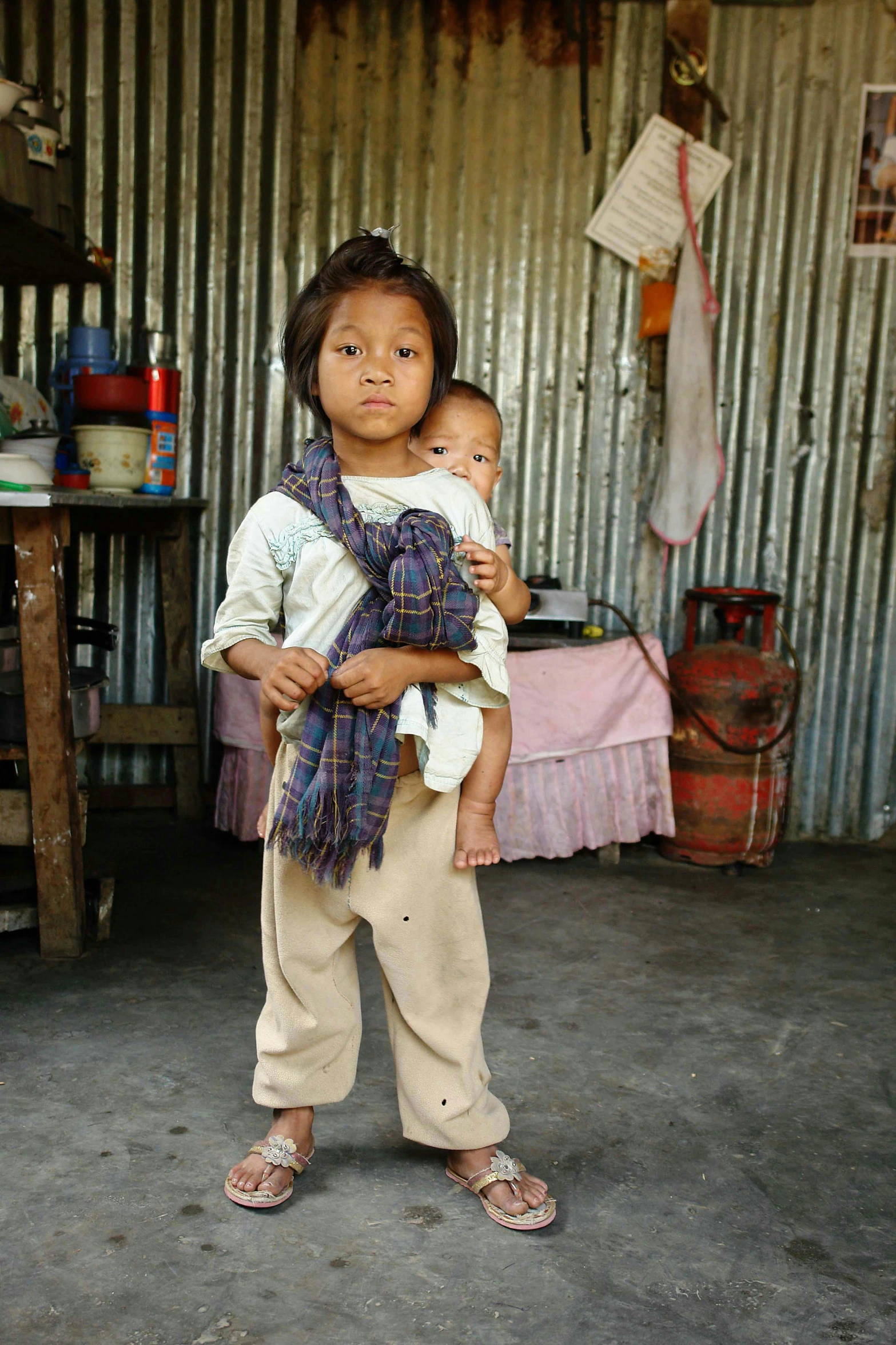 a little boy standing in a room holding a baby