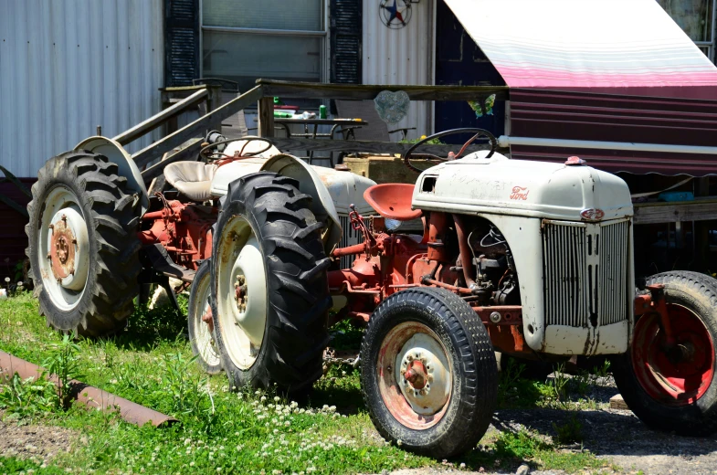 four old tractors parked in front of a red barn