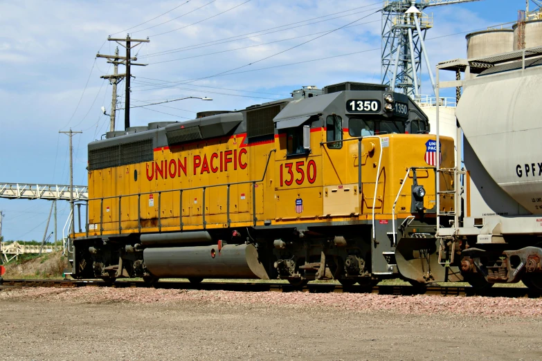 an orange and white train traveling past a large gray truck