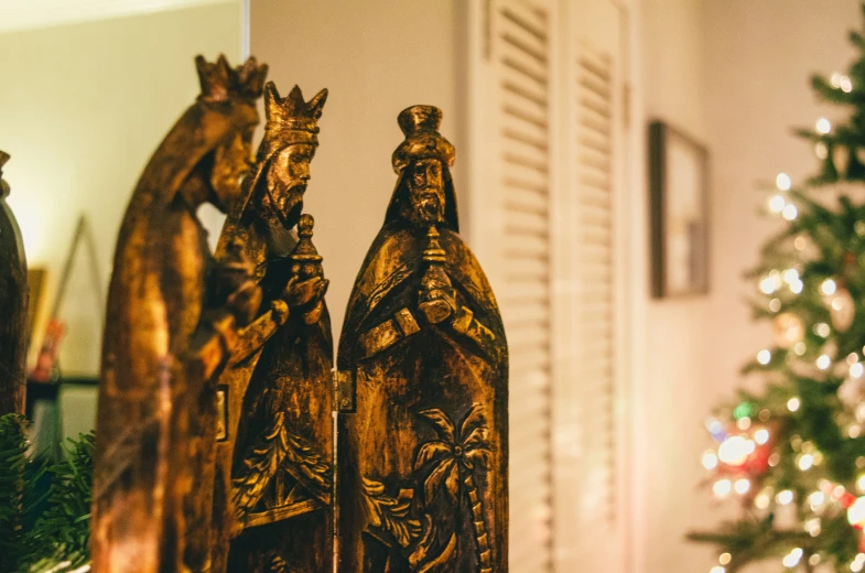 two statues on a shelf with a christmas tree behind them