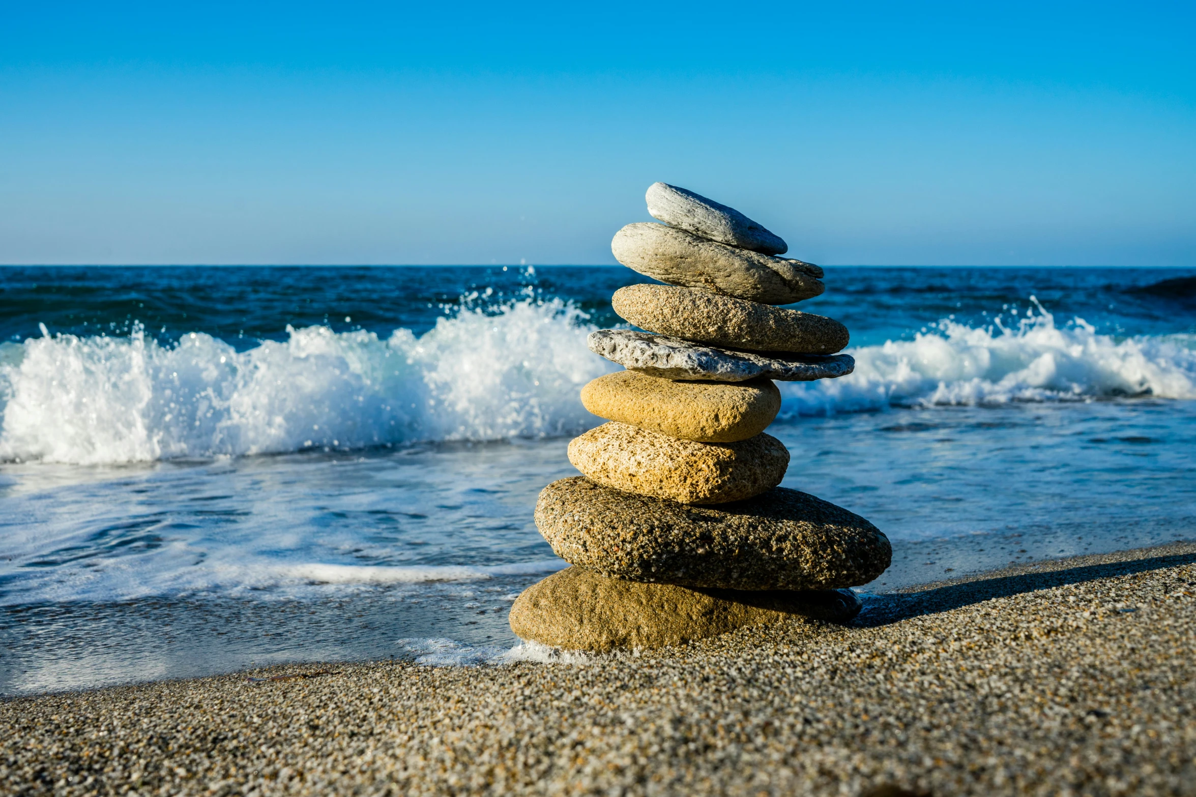 stacked rocks sit on the beach next to the ocean