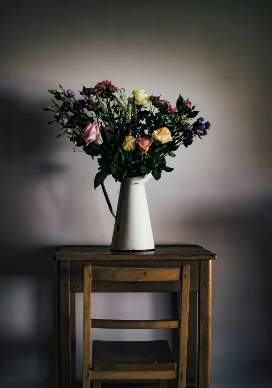 flowers are in a white vase next to a small table