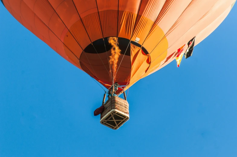 an orange and black balloon flying in a blue sky