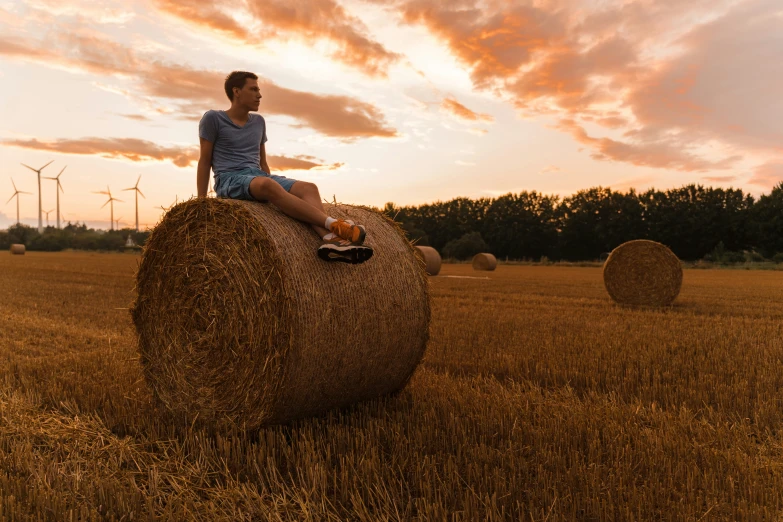 a man sitting on top of a large bale of hay