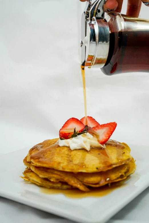 a stack of pancakes being prepared with syrup