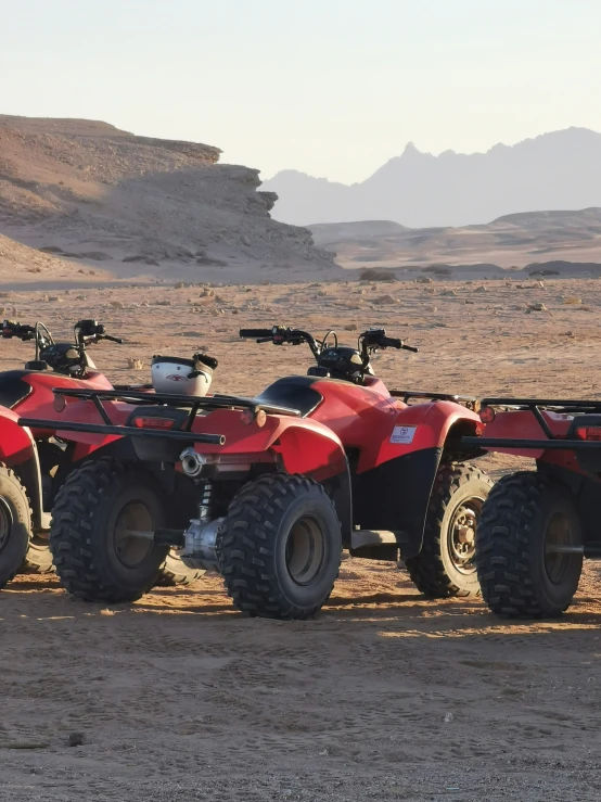 a row of three atvs sitting in the desert