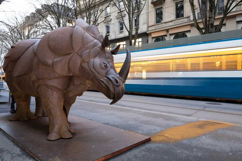 a sculpture of a rhino that is sitting on a sidewalk