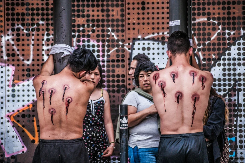 several people standing by a wall with paint splattered on them