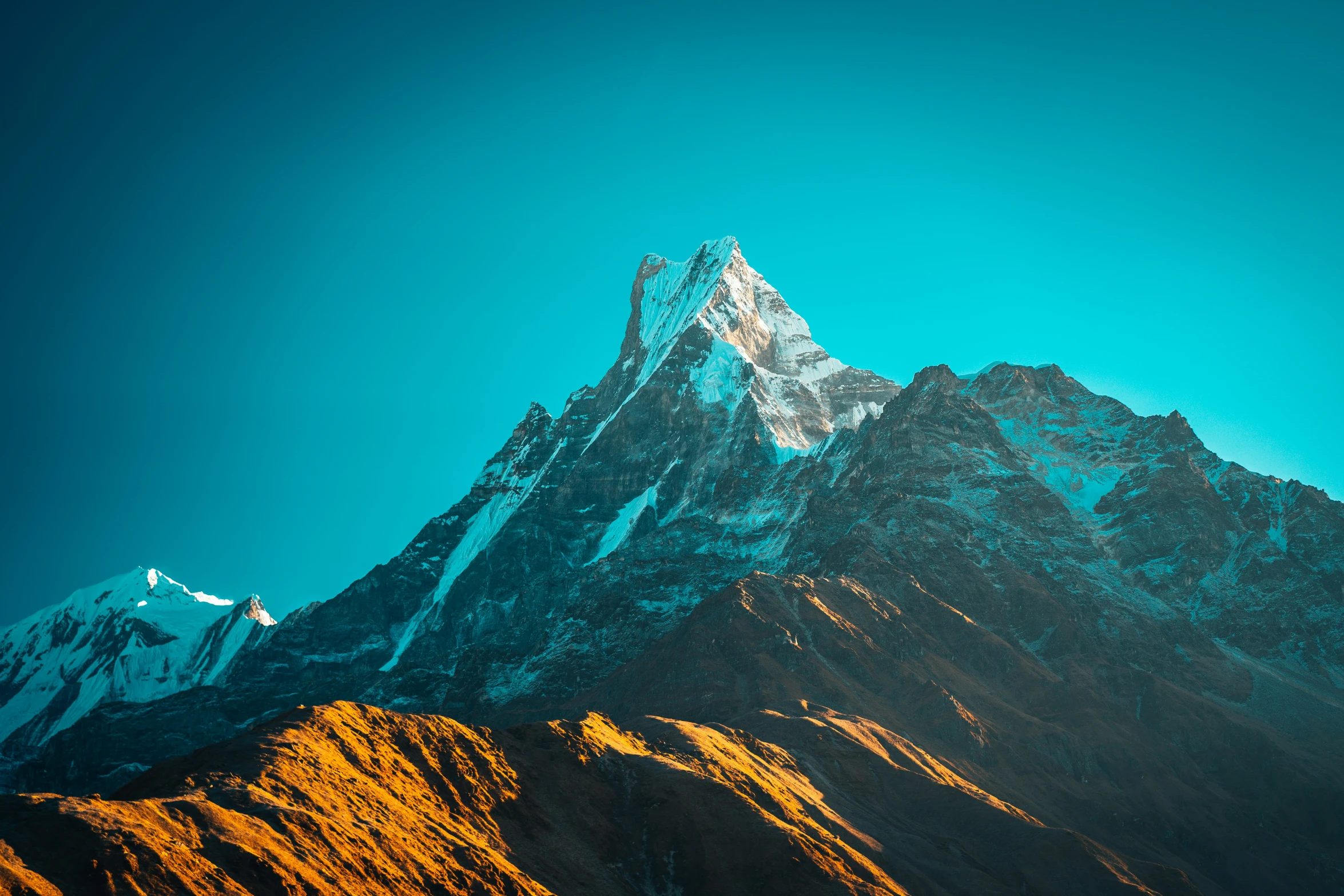 the large snow covered mountain is lit up in a blue sky