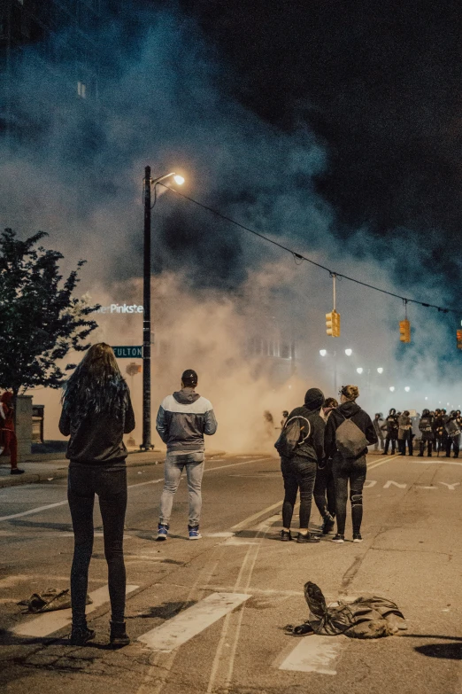 several people stand on a street corner while the storm comes