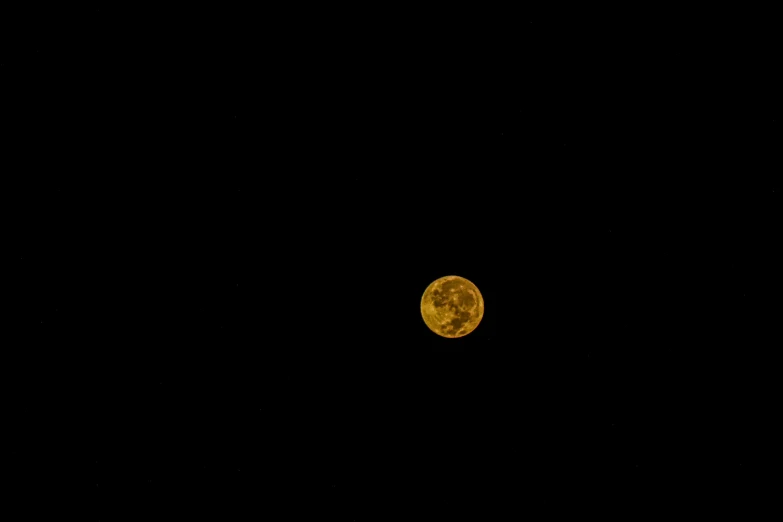 an orange moon rising above the black sky