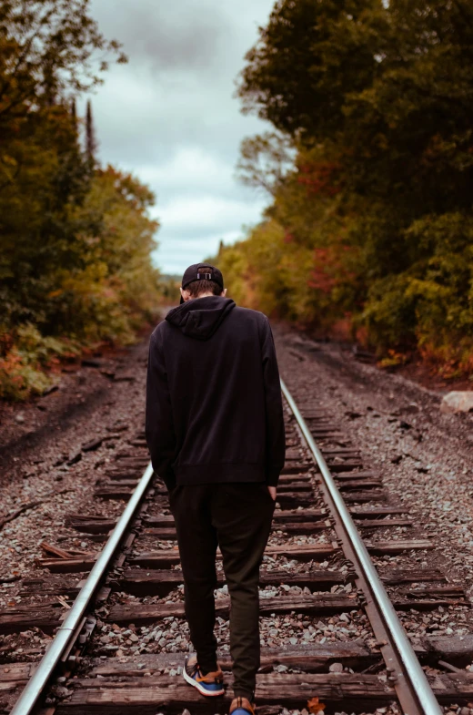 a person standing on train tracks between trees