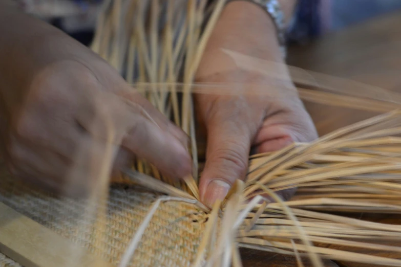 two hands are pulling straw from a table