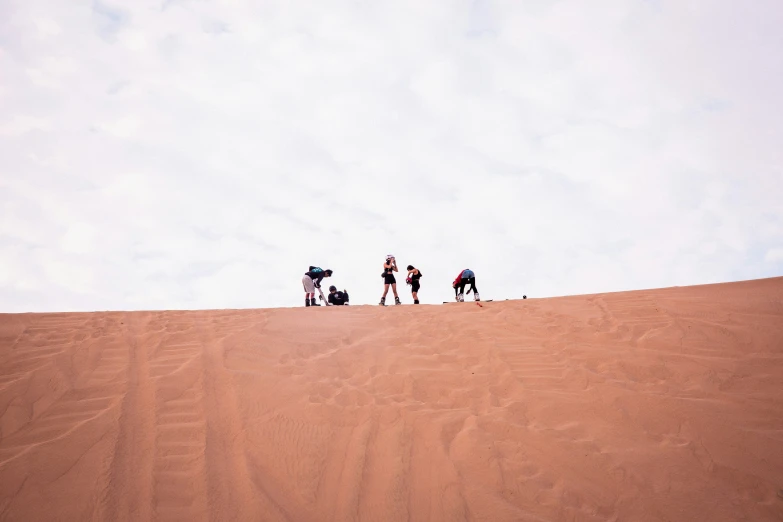 three people in the desert on camels and a dog