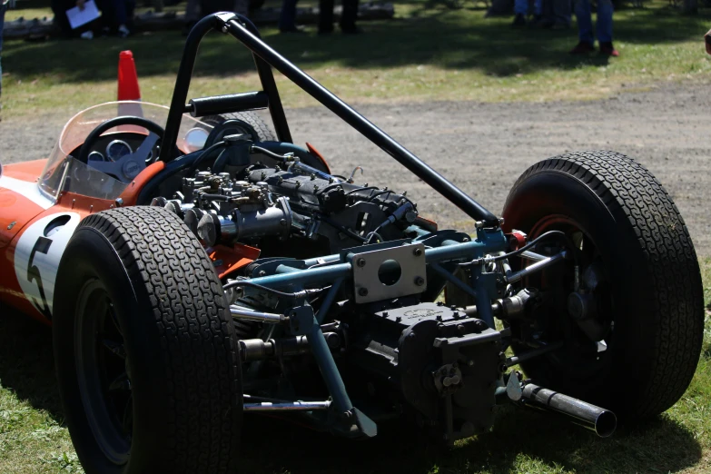 an orange race car with two engine parts sitting on a grassy area