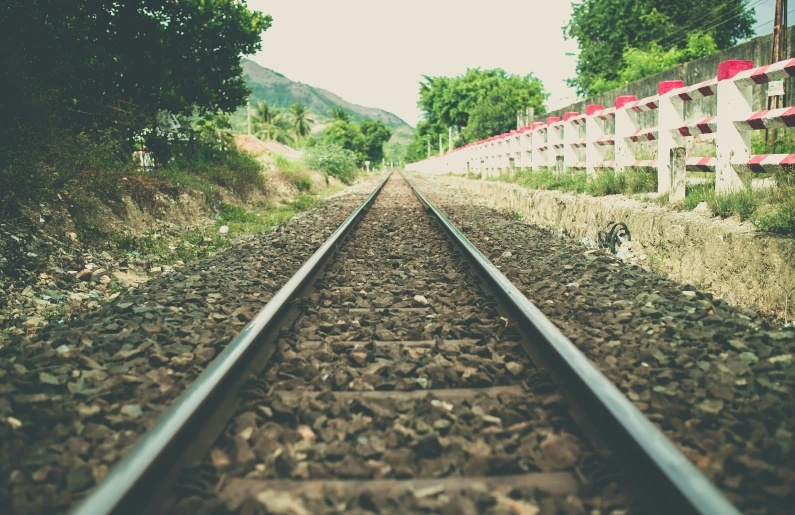 a po of railroad tracks with a building and trees in the background