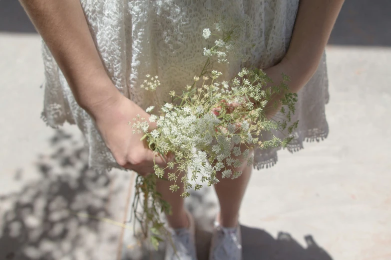 a woman with white shoes holding a bunch of plants