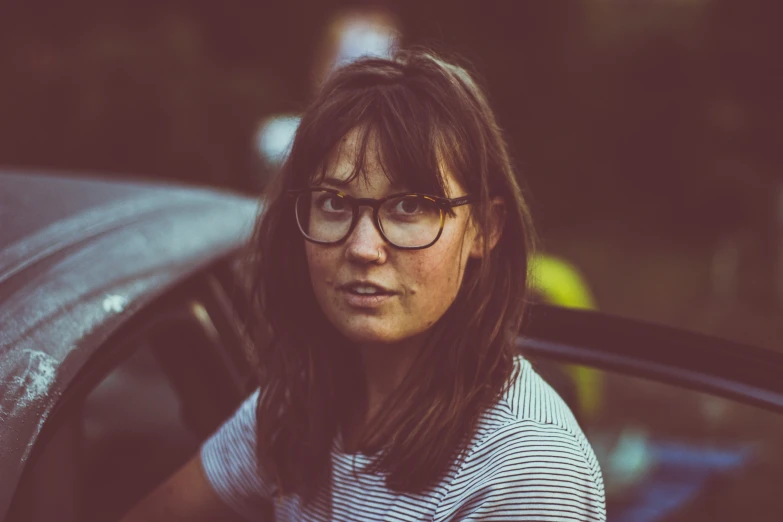 a woman with glasses leaning out the window