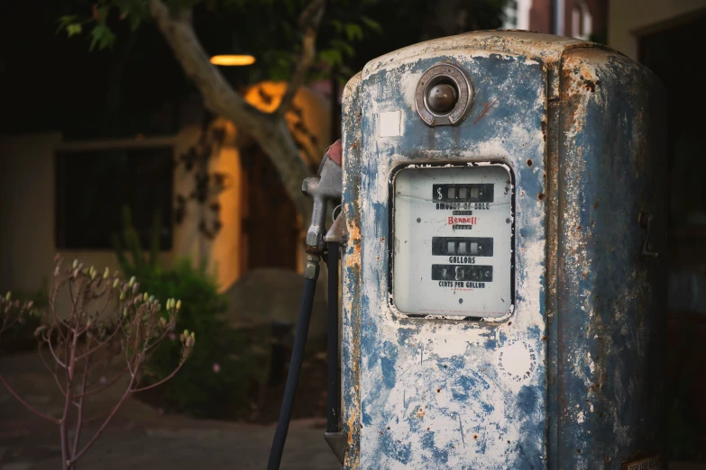 an old rusty fuel pump in a driveway