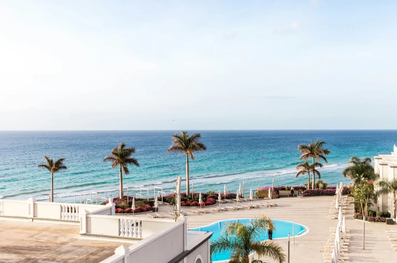 a beach with a pool and a long white wall on the right