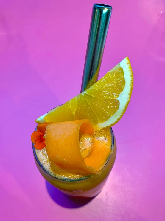 a lemon drink with a straw and orange slices on the rim